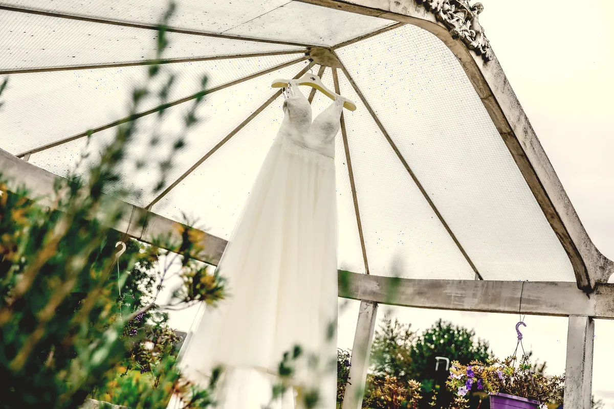 La robe de mariée suspendue sous une tonnelle.