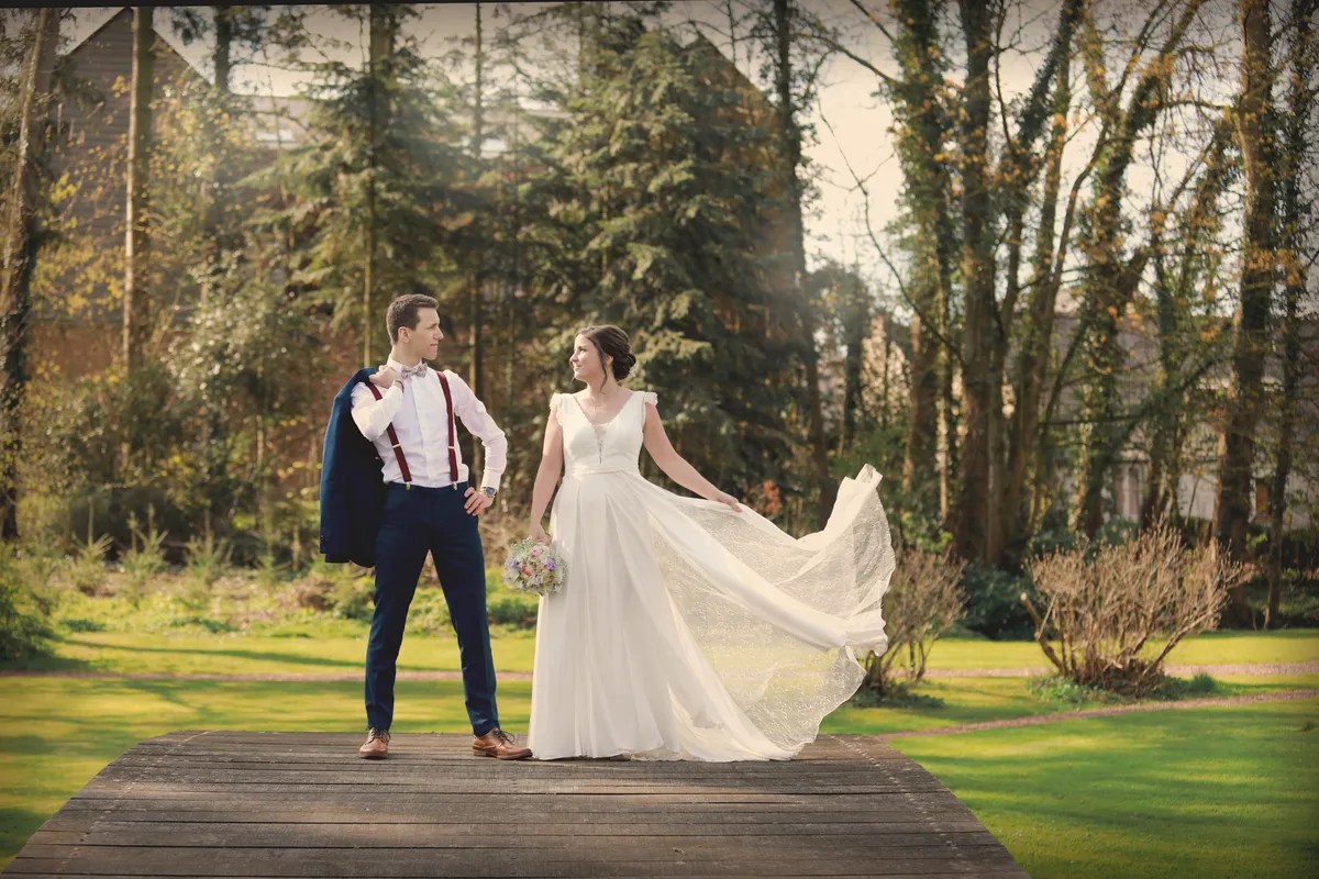 Les mariés dans un parc, la robe soulevée par le mouvement.