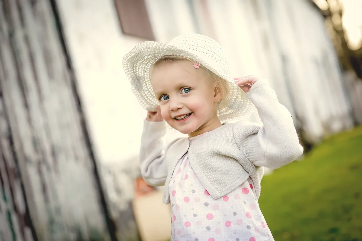 Une fillette en chapeau blanc, tout sourire.