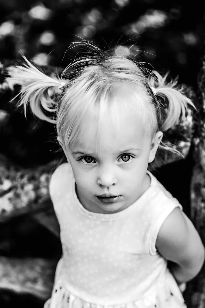 En noir et blanc, une petite fille aux couettes regarde l’objectif.