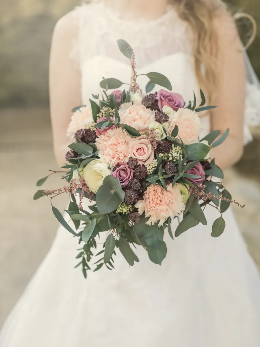 Le bouquet de roses et de pivoines, tenu contre la robe.