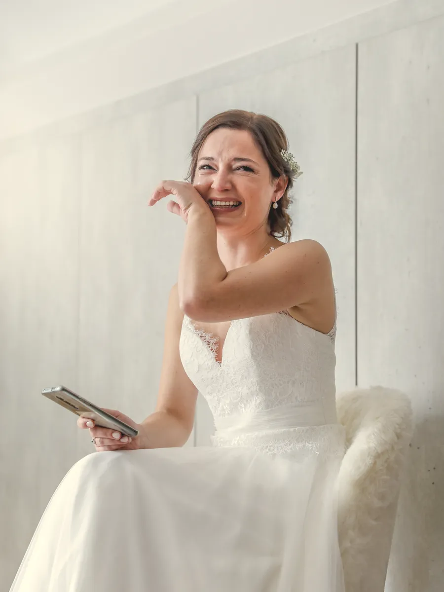 La mariée lit une lettre et essuie une larme en riant.