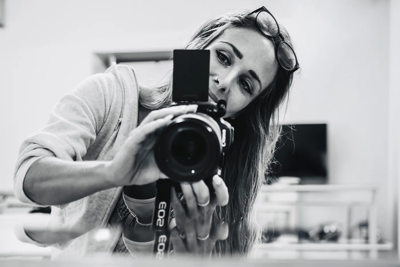 Autoportrait en noir et blanc de Charlotte Doulière, son appareil photo à la main.